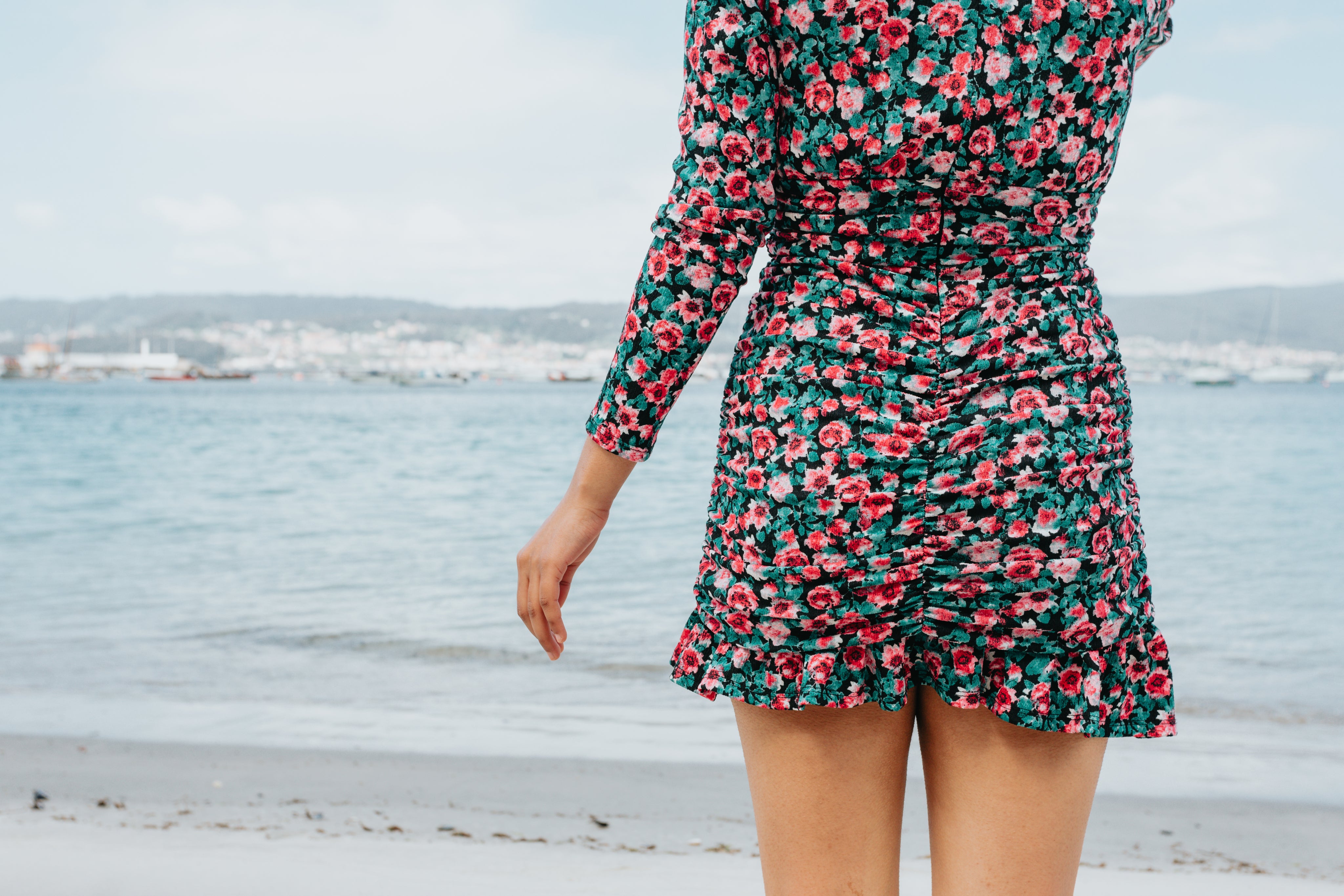 files/person-in-a-floral-dress-stands-on-a-beach-facing-the-water.jpg